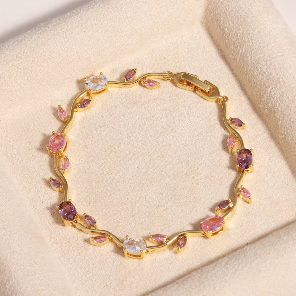 Gold floral gemstone bracelet arranged in a circle on beige fabric