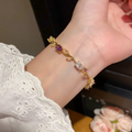 Wrist shot of gold bracelet with pink and purple gemstone floral design