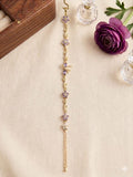 Gold floral amethyst bracelet displayed on cream fabric with purple flower and decorative glass bottles