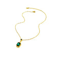 Gold chain necklace with rectangular green gemstone pendant bordered by clear crystals on a white background