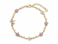 Gold floral bracelet laid flat, showing alternating purple and white flower charms and leaf accents with adjustable chain